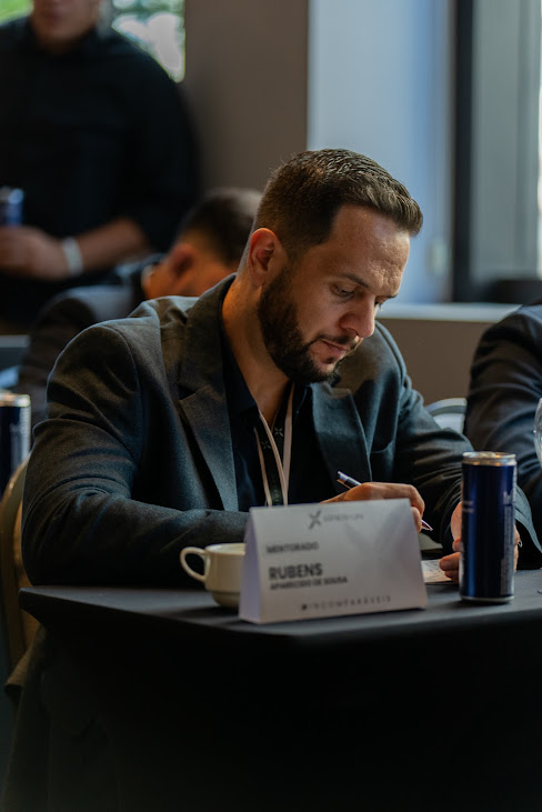 Rubens Sousa tomando notas durante um evento presencial de negócios